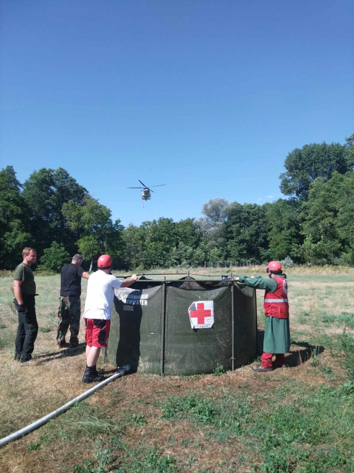 Волонтери на Црвен крст поставија мобилен резервоар за вода од каде хеликоптери црпеа вода за гаснење на големиот шумски пожар  